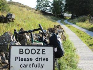 Image of approach lane to hamlet of Booze, in north Yorkshire, showing sign saying 'BOOZE Please drive carefully', with bicycle behind
